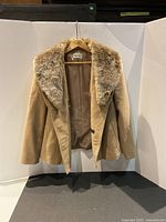 Beige women's coat hanging, showing the front and faux fur collar detail.