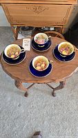 Four teacups and saucers arranged on wooden table, full lot view