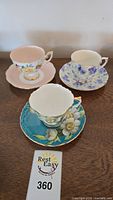 Photo showing three teacup and matching saucer sets with different floral patterns and colors