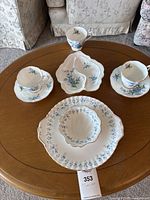Photo of entire Royal Albert Forget Me Not set placed on a wooden table including plates, teacups, saucers and relish dish