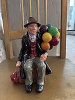 Front view of Royal Doulton vintage Balloon Man figurine seated holding colorful balloons.