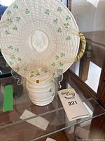 View of the plate displayed upright with lidded jar in front, shows shamrock design and wicker-style handles, and lot number card.