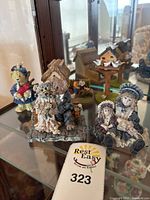 Photo of vintage Dollstone figurines and additional decorative items arranged in glass curio shelf, showing textures and size relative to environment.