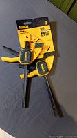 Two yellow and black DeWalt 6 inch medium trigger clamps still attached to original packaging.