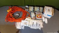 Photo of the electrical lot items laid out showing extension cord, plates, boxes, wire nuts, and outlets grouped on a surface.