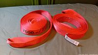 Two red Husky straps rated for 7000 lbs, rolled and placed on a flat surface.