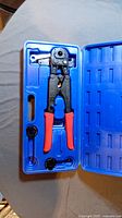 Full image of the PEX crimper tool with carrying case and red handles.