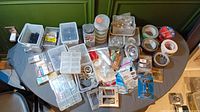 Overview of lot contents on table showing bins of screws, nails, tapes, plumbing drain parts and various hardware items