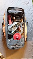 Top-down view into open Rigid tool bag showing assorted metal hardware pieces and a red spool.