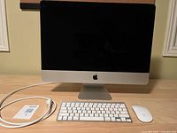 Front view of Apple iMac with Magic Keyboard, Magic Mouse, and power cable on desk