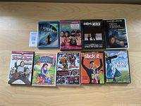 Nine assorted DVDs arranged on a wooden surface showing front covers