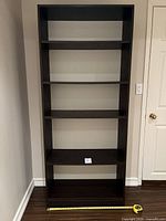 Front view of the dark brown bookshelf showing five shelves and minor scratches.