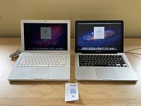 Front view of two laptops turned on, showing Mac OS X screens. White MacBook 2008 on left, silver MacBook Pro 2012 on right.