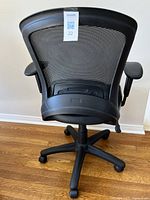 Rear view of the office chair showing black mesh back and adjustable armrests