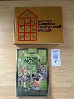Top view of two books showing covers: Reader's Digest Complete Do-it-yourself Manual in gold and Fix Your Bicycle with illustrated cover