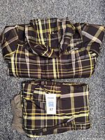 Folded plaid Burton jacket and pants showing the pattern and size tag.
