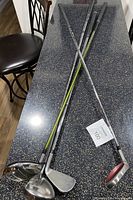 Four men's left-handed golf clubs shown laid out on a table, displaying shafts, grips, and club heads.