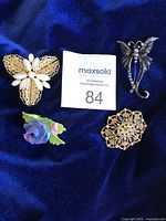 All 4 vintage brooches shown on dark blue fabric background.