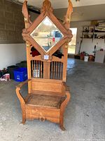 Full front view of the oak hall tree showing crest, mirror, hooks, spindles, armrests and bench