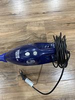 Close-up image of the vacuum's handheld unit with Black & Decker branding and coiled power cord