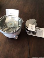 Photo of rice cooker with operating instructions and accessories inside the bowl.