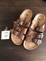 Top view of brown Mephisto leather sandals with two adjustable buckles on each sandal, showing the insole and brand logo.