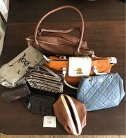 Various purses and handbags including a large brown leather Lodis bag, a cream and rust colored large bag, small patterned bags, and a blue quilted bag.