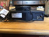 Rear side view of Sharp VHS HQ VCR showing connection ports, power cord, and labels.