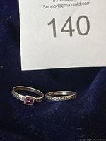 Two-piece sterling silver ring set shown on dark fabric background with lot number visible.