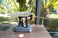 Side view of the antique scale showing the brass tray and cast iron base with wear.