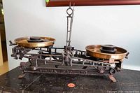 Front view of entire cast iron balance scale with brass pans and stacked weights