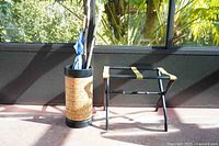 Wide shot showing the walking sticks, golf umbrella in the decorative cork holder, and the black luggage rack.