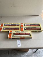 Five boxed HO scale passenger cars on a beige table, showing full lot contents and original packaging.