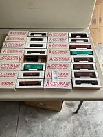 Top view of 14 Accurail HO scale model train cars inside original white packaging with red logo, arranged in rows on a table.
