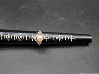 Front view of the ring on a black ring sizer showing the 5mm pearl and diamond accents.