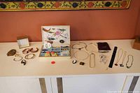 Wide view of all assorted vintage costume jewelry laid out including pins, earrings, necklaces, bracelets, and the vintage jewelry box.