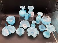 Full assortment of vintage Fenton baby blue glass pieces with soft ruffled edges, shown arranged on two levels with central lot number card.