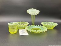 Front view of all five pieces: bud vase centered, tumbler left, two oval dishes and one round ruffled dish front