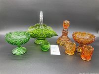 Photo showing full assortment including apple green handled basket, candy dish, small toothpick holder, amber moon candle holder, two toothpick holders, compote dish