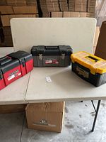 Three toolboxes on a table: one red Craftsman, one gray Craftsman, one black and yellow Voyager