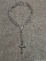 Full view of the rosary beads laid out showing clear faceted stones and silver chain links.
