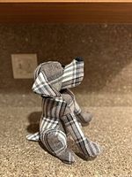 Side angle of the gray plaid dog-shaped door stopper showing texture and shape.