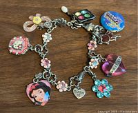 Top-down view of Hello Kitty charm bracelet on wooden surface, showing all charms and details clearly