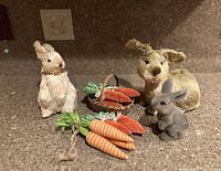 Front view of lot showing textured beige and gray bunny figurines along with plush carrots and a basket.