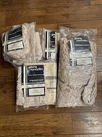 Four packages of vintage, new in bag Croscill Young Romantics champagne color curtains set on wooden floor.