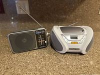 Panasonic and Lauson portable radios side by side on countertop showing overall condition and design features.