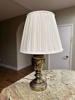 Front view of vintage Stiffel brass table lamp with white pleated shade on marble surface