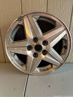 Front view of the 17-inch alloy wheel showing five-spoke design with angular ridge accents, surface oxidation and minor wear visible.