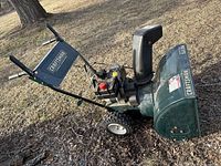 Full side view of Craftsman snowblower showing chute, engine, wheels, and handles outdoors on dry grass.
