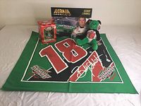 Photo showing all items in the lot including autographed bandana, diecast car in box, green plush bear, and media card.